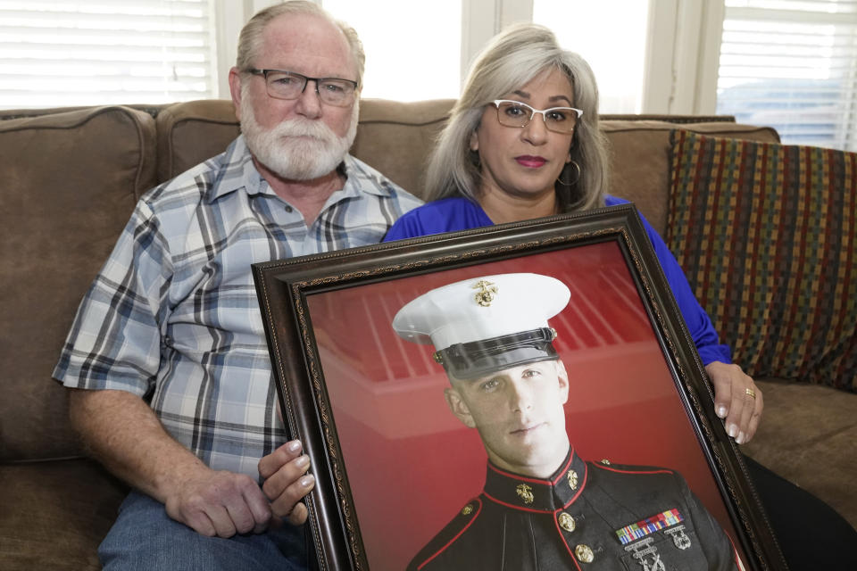 Joey and Paula Reed pose for a photo with a portrait of their son Marine veteran and Russian prisoner Trevor Reed at their home in Fort Worth, Texas, Tuesday, Feb. 15, 2022. Russia is holding Trevor Reed, who was sentenced to nine years on charges he assaulted a police officer. (AP Photo/LM Otero)