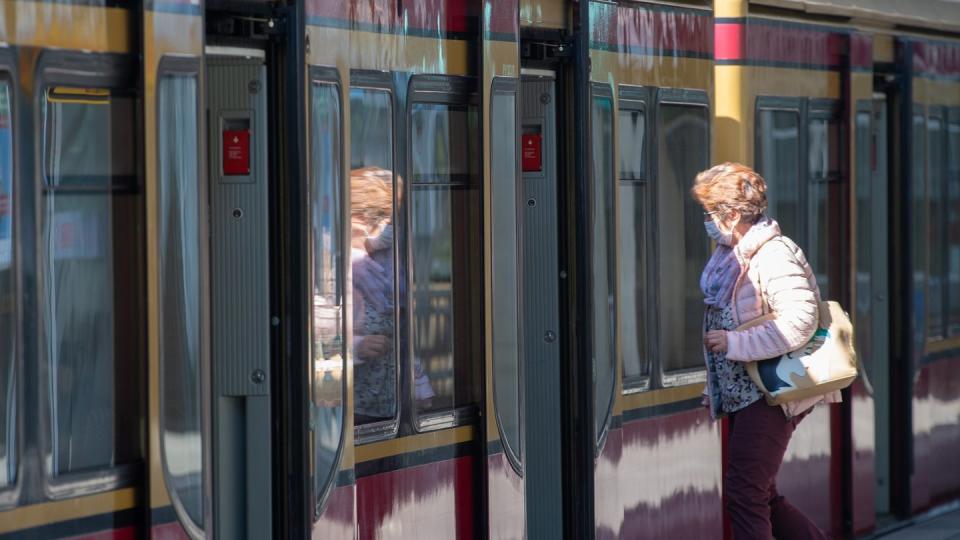 Eine Frau mit Mundschutz steigt in eine Berliner S-Bahn ein.