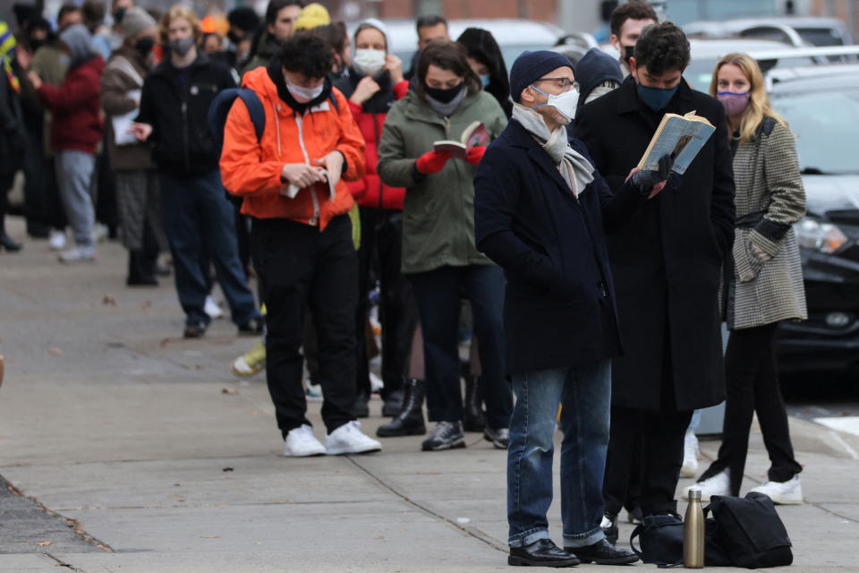 A person reads a book while standing in line for a mobile COVID-19 testing unit as the Omicron coronavirus variant continues to spread in Manhattan, New York City, U.S., December 18, 2021. REUTERS/Andrew Kelly