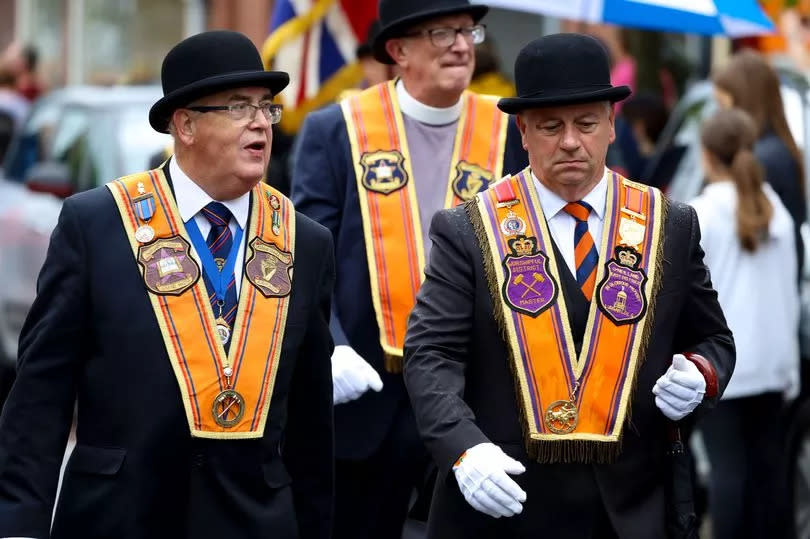 Orangemen in collarettes march on the Twelfth