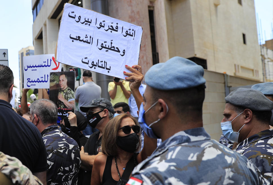 A woman who lost her relative during the last year's massive blast at Beirut's seaport, holds an Arabic placard that reads:"You exploded Beirut and you put the people in the coffin," during a protest near the tightly-secured residents of parliament speaker Nabih Berri, in Beirut, Lebanon, Friday, July 9, 2021. The protest came after last week's decision by the judge to pursue senior politicians and former and current security chiefs in the case, and requested permission for their prosecution. (AP Photo/Hussein Malla)