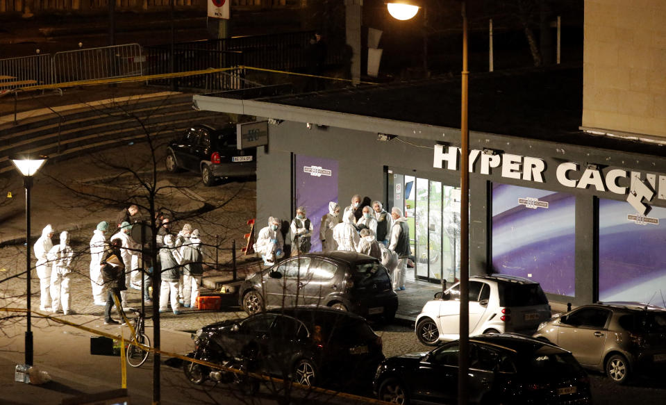 FILE - In this Jan. 9, 2015 file photo, forensic officers gather outside a kosher grocery store which was the scene of a hostage taking in Paris. The January 2015 attacks against Charlie Hebdo and, two days later, a kosher supermarket, touched off a wave of killings claimed by the Islamic State group across Europe. Seventeen people died along with the three attackers. Thirteen men and a woman accused of providing the attackers with weapons and logistics go on trial on terrorism charges Wednesday Sept. 2, 2020. (AP Photo/Francois Mori, File)