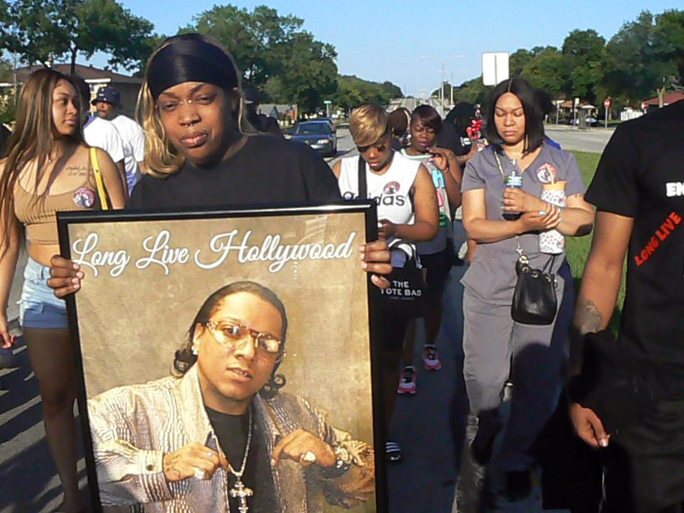 Family and friends of Ronald Butler gathered at the spot where his van came to rest after he was fatally shot on July 19, 2022. One of his three sisters, Victoria Butler, holds a picture of him.