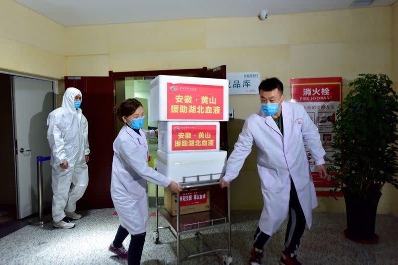 Los miembros del personal que llevan máscaras faciales mueven los suministros de sangre para ser enviados a Wuhan, el epicentro del nuevo brote de coronavirus, en un centro de sangre en Hefei, provincia de Anhui, China