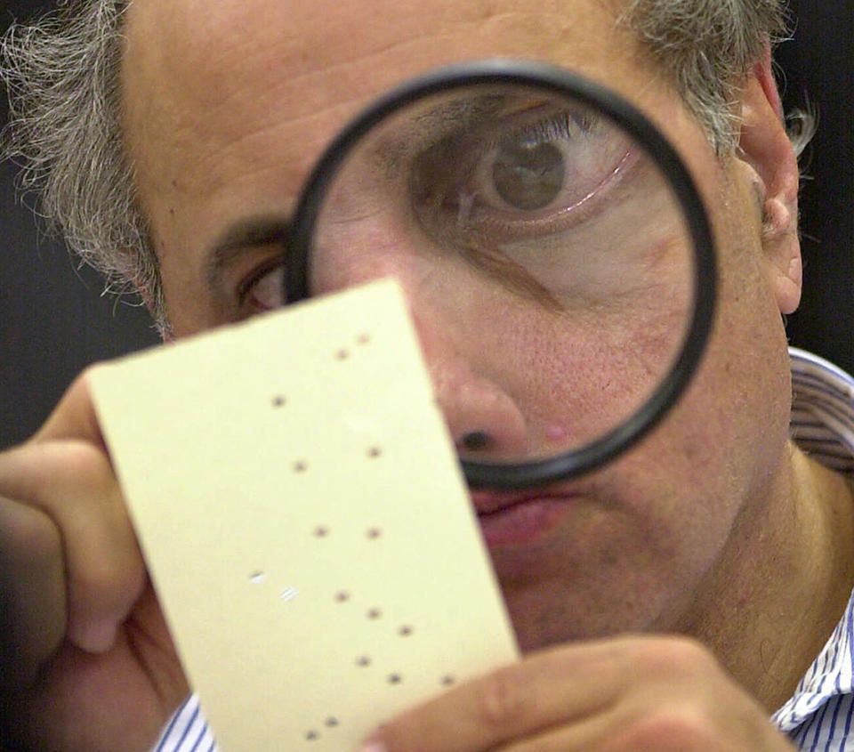 In this Nov. 24, 2000, file photo, Broward County, Fla. canvassing board member Judge Robert Rosenberg uses a magnifying glass to examine a disputed ballot at the Broward County Courthouse in Fort Lauderdale, Fla. (AP Photo/Alan Diaz)