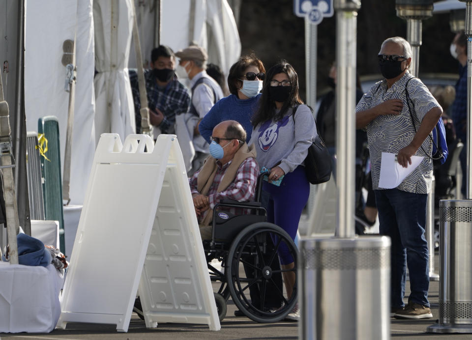 Orange County residents wait in line outside tents for a COVID-19 vaccine at the Toy Story parking lot at the Disneyland Resort Wednesday, Jan. 13, 2021, in Anaheim, Calif. The parking lot is located off Katella Avenue and sits southeast of Disneyland. California is immediately allowing residents 65 and older to get scarce coronavirus vaccines, Gov. Gavin Newsom announced Wednesday. (AP Photo/Damian Dovarganes)