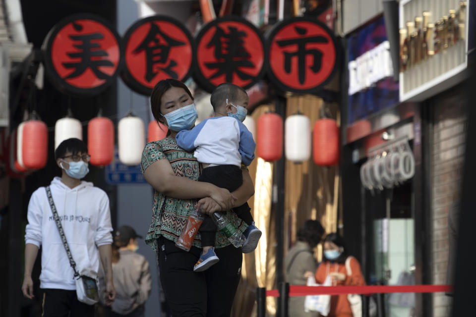 Residents wearing masks to help curb the spread the coronavirus walk along a retail street in Wuhan in central China's Hubei province on Thursday, April 9, 2020. Released from their apartments after a 2 1/2-month quarantine, residents of the city where the coronavirus pandemic began are cautiously returning to shopping and strolling in the street but say they still go out little and keep children home while they wait for schools to reopen. (AP Photo/Ng Han Guan)