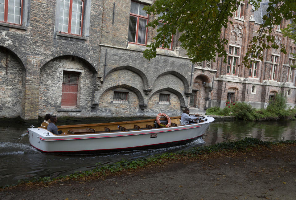 A tour boat operator drives his nearly empty boat down a canal in Bruges, Belgium, Wednesday, Sept. 2, 2020. Tourism sector losses have piled up in the tens of billions of euros across the 27-nation European Union, and the continent's vaunted government support and social security system is under increasing strain to prop up the sector. (AP Photo/Virginia Mayo)