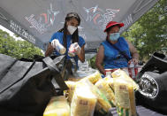 Volunteers Vanessa Sheffield, left, and Anakarina, who declined to give her last name, load food into bags at a food and mask distribution site put on by the Miami Marlins baseball organization, Monday, June 29, 2020, outside Marlins Park stadium in Miami. (AP Photo/Wilfredo Lee)