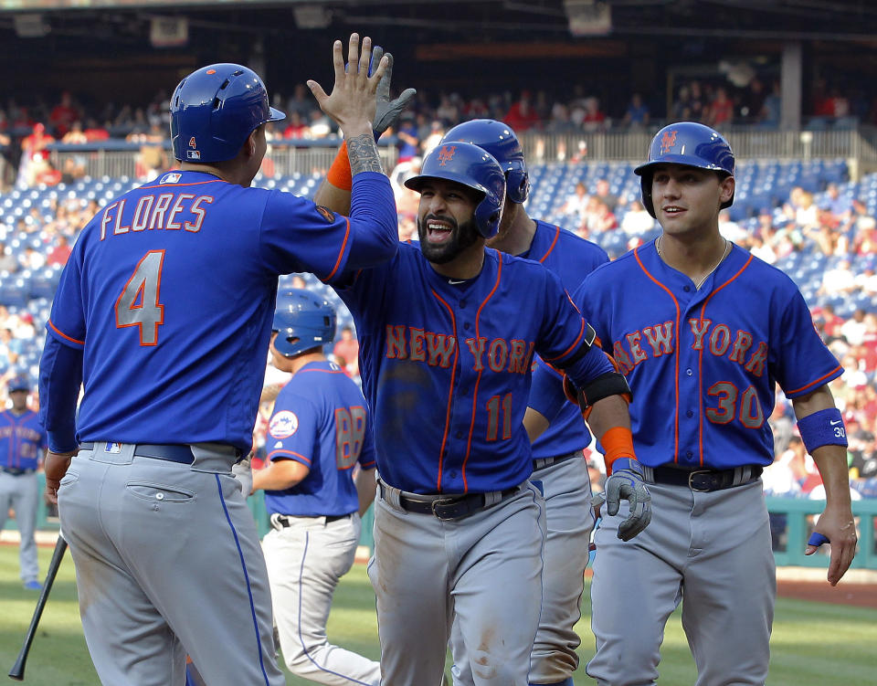 New York Mets' Jose Bautista, center, high-fives Wilmer Flores after Bautista hit a grand slam during the fifth inning of a baseball game against the Philadelphia Phillies, Thursday, Aug. 16, 2018, in Philadelphia. (AP Photo/Tom Mihalek)