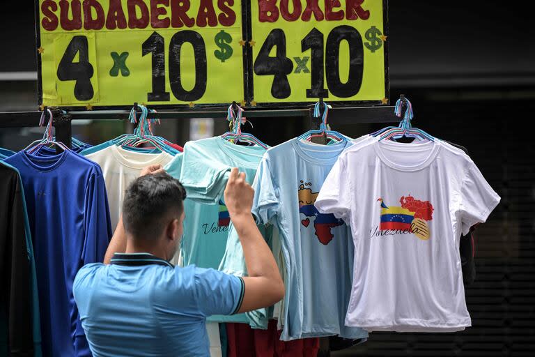 Un vendedor ambulante de ropa coloca sus productos en la calle con precios en dólares estadounidenses en Caracas, el 23 de julio de 2024