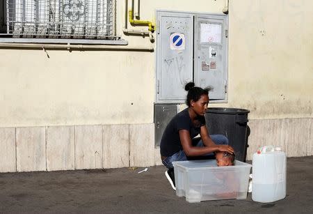 A migrant washes her baby at a makeshift camp in Via Cupa (Gloomy Street) in downtown Rome, Italy, August 1, 2016. REUTERS/Max Rossi