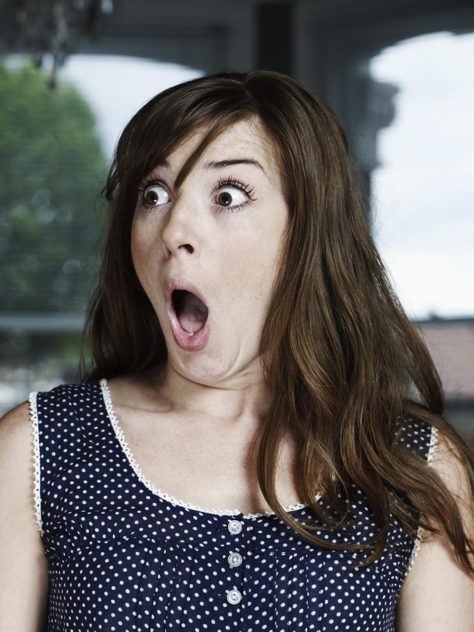 Young white woman with brown long hair looking shocked at something outside of the frame