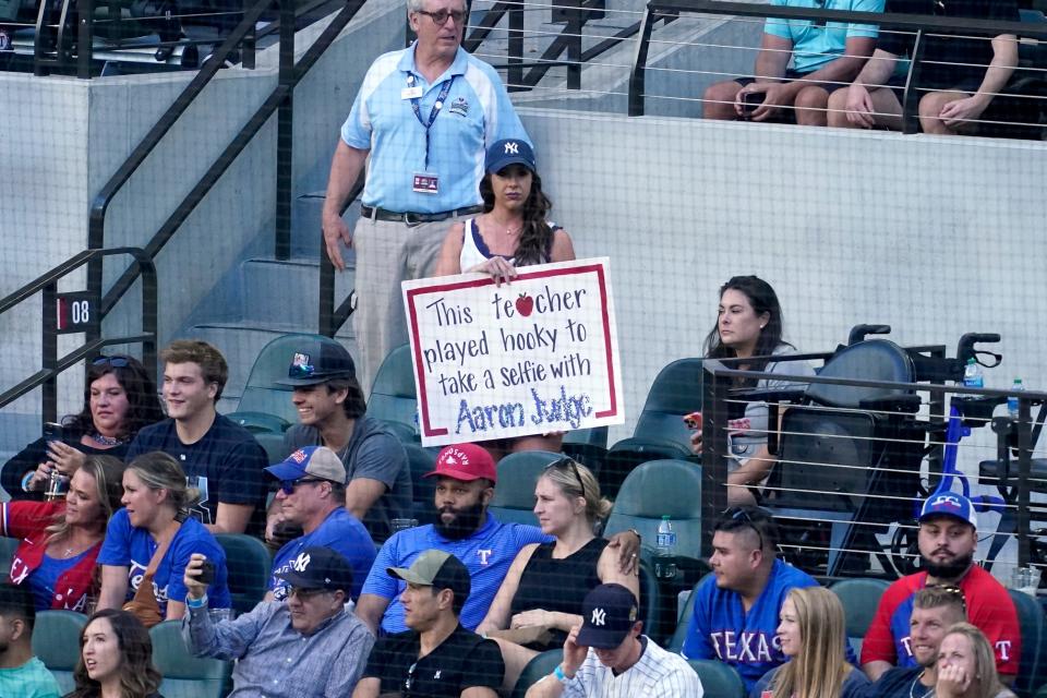 A fan holds a sign making reference to New York Yankees' Aaron Judge as she watches play in the ninth inning of the Yankees' baseball game against the Texas Rangers in Arlington, Texas, Wednesday, Oct. 5, 2022. (AP Photo/Tony Gutierrez)