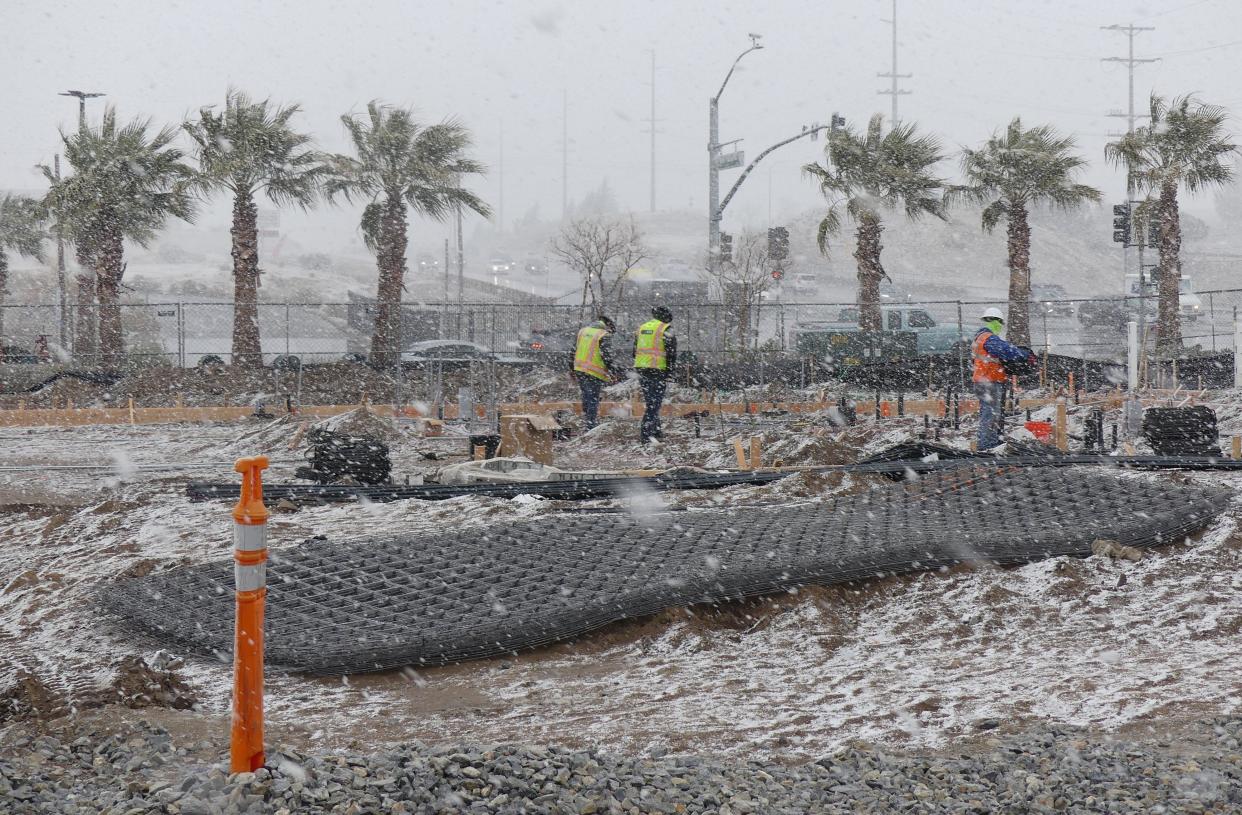 A construction crew in the snow works on the new Panera Bread restaurant. Snow fell on Thursday across the High Desert, with a blizzard expected in the local mountain on Friday and Saturday.
