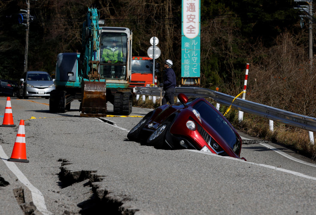 日本石川地震後一輛汽車卡在道路裂縫中的景象。（路透社）