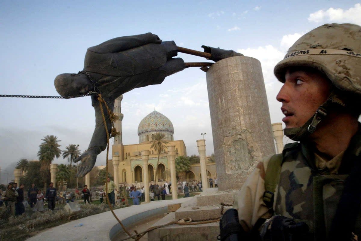 A US marine watches as the statue of Saddam Hussein falls in central Baghdad's Firdaus Square, 9 April, 2003 (Reuters)