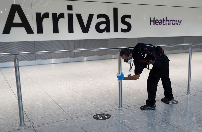 FILE PHOTO: A worker sanitises a barrier at the International arrivals area of Terminal 5 in London's Heathrow Airport