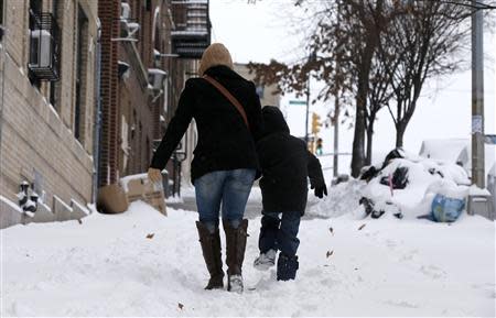 A woman and her son make their way up a snow covered sidewalk in the South Bronx section of New York City, January 3, 2014. REUTERS/Mike Segar