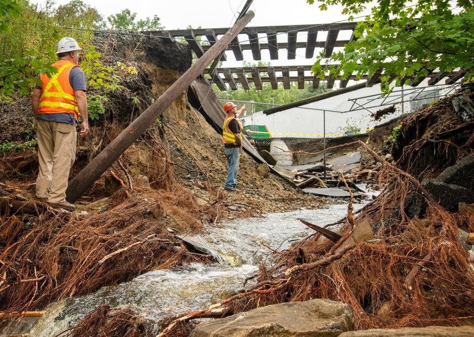 Railroad workers examine an undermined railroad bed in North Leominster the morning after flash floods hit the area Sept. 12, 2023.