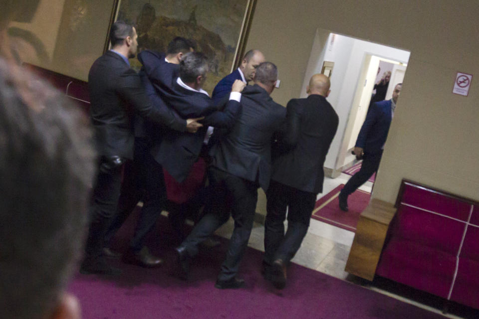 Police officers carry a pro-Serb opposition lawmaker in the parliament building in Podgorica, Montenegro, Friday, Dec. 27, 2019. The Serbian Orthodox Church says the law will strip it of its property, including medieval monasteries and churches. The government has denied that. Montenegro's parliament adopted a contested law on religious rights after chaotic scenes in the assembly that resulted in the detention of all pro-Serb opposition lawmakers. (AP Photo)