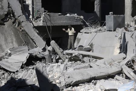 A man reacts amid rubble from what activists said was barrel bombs dropped by forces loyal to Syria's President Bashar Al-Assad in Douma, eastern Ghouta, near Damascus, Syria August 22, 2015. REUTERS/Bassam Khabieh - RTS6ALL