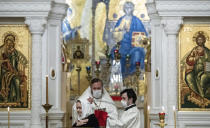 An orthodox priest wearing a face mask to protect against coronavirus distributes Holy Communion during a service at the Christ the Savior Cathedral in Moscow, Russia, Tuesday, June 2, 2020. Churches in Moscow reopen to believers after a two-month lockdown imposed to control the spread of the coronavirus. (AP Photo/Pavel Golovkin)