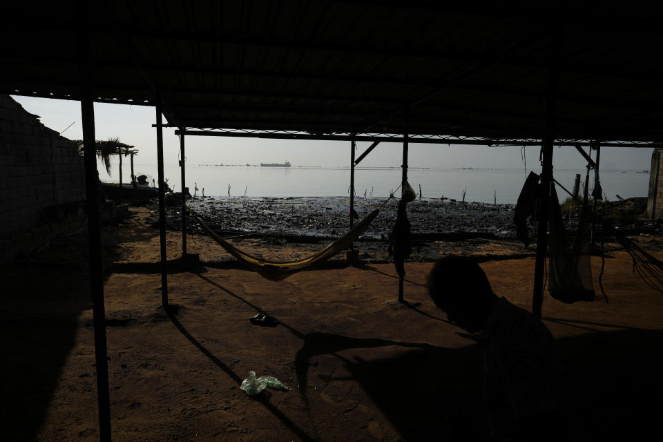 Thatched roof huts line the shore of Lake Maracaibo contaminated with oil and aquatic trash, in San Francisco, Venezuela, Wednesday, Aug. 9, 2023. The pollution around the lake, one of Latin America's largest, is the result of decades of excessive oil exploitation on its bed, inadequate maintenance, and a lack of investment to improve an already obsolete infrastructure, according to environmentalists. (AP Photo/Ariana Cubillos)