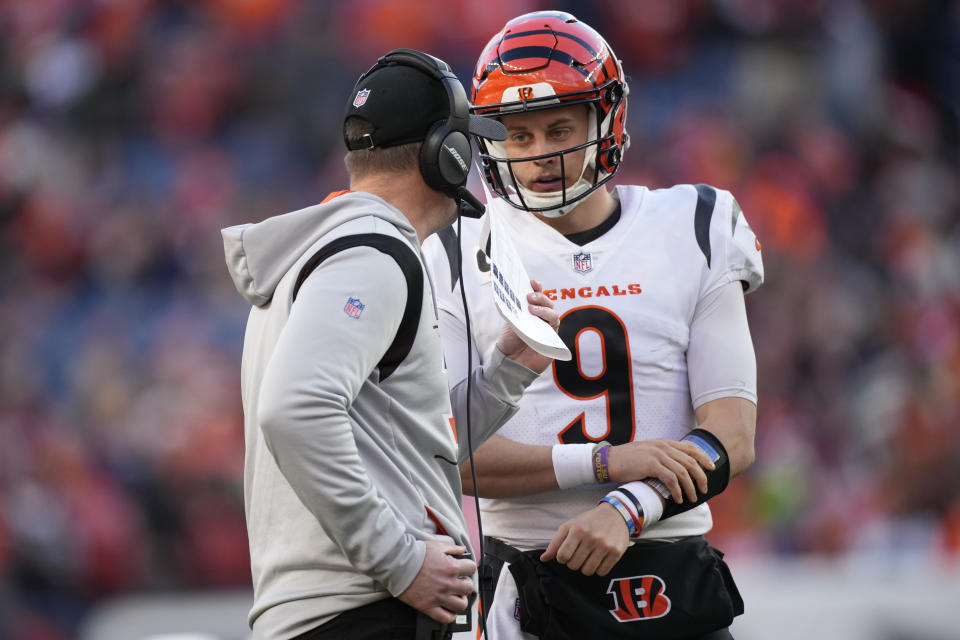 Cincinnati Bengals quarterback Joe Burrow (9) talk with head coach Zac Taylor during the first half of an NFL football game against the Denver Broncos, Sunday, Dec. 19, 2021, in Denver. (AP Photo/David Zalubowski)