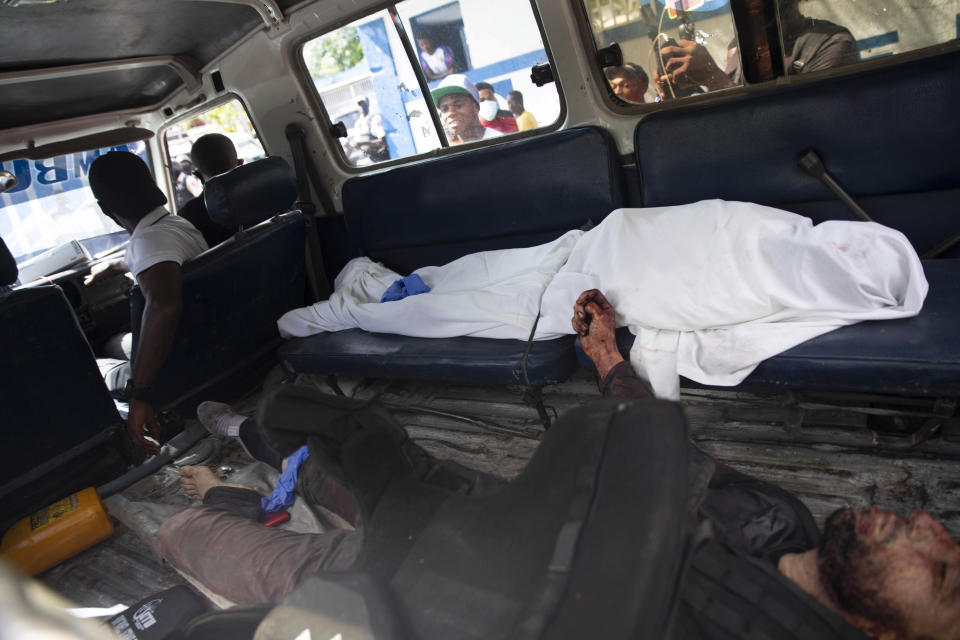 People look into the window of a police car carrying the bodies of two people killed in a shooting with police in Port-au-Prince, Haiti, Thursday, July 8, 2021. According to Police Chief Leon Charles, the two dead are suspects in the assassination of Haitian President Jovenel Moïse. (AP Photo/Joseph Odelyn)