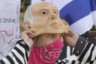 A protester wears a bandana as a face mask as he pulls on a rubber mask representing Israeli Prime Minister Benjamin Netanyahu outside of the Knesset in Jerusalem, Thursday, Sept. 24, 2020, after Israel moved to further tighten its second countrywide lockdown as coronavirus cases continue to soar. Prayers during the ongoing Jewish High Holidays, as well as political demonstrations, would be limited to open spaces and no more than 20 people, and participants would have to remain within the restricted distance from home. (AP Photo/Maya Alleruzzo)