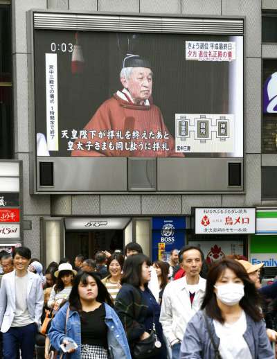 大阪街頭的大型螢幕30日上午報導明仁天皇退位的消息，不過明仁參加相關儀式的虔敬神情，與街上熙來攘往的日本人民形成有趣對比。（美聯社）