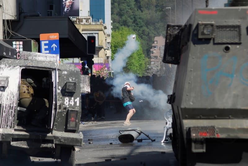 A demonstrator throws a tear gas canister back to officers of the Chilean police during a protest against social inequality in Concepcion