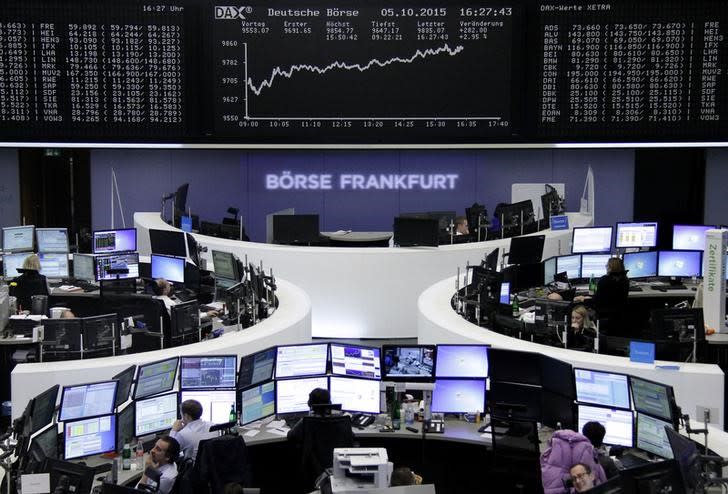 Traders are pictured at their desks in front of the DAX board at the stock exchange in Frankfurt, Germany, October 5, 2015. REUTERS/Staff/remote