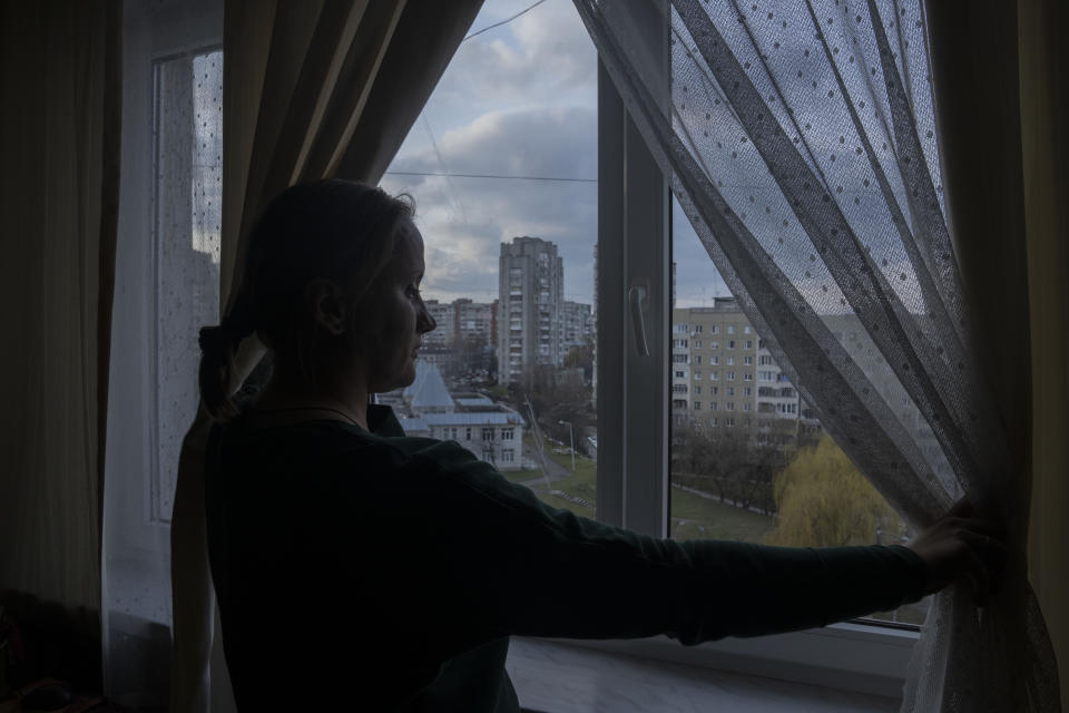 Olha Salivonchuk, head of the local association of apartment owners, looks out of the window in her living area, at her apartment, in Lviv, western Ukraine, Sunday, April 3, 2022. Olha has never considered leaving, even when a Russian airstrike in Lviv made their building shake. (AP Photo/Nariman El-Mofty)