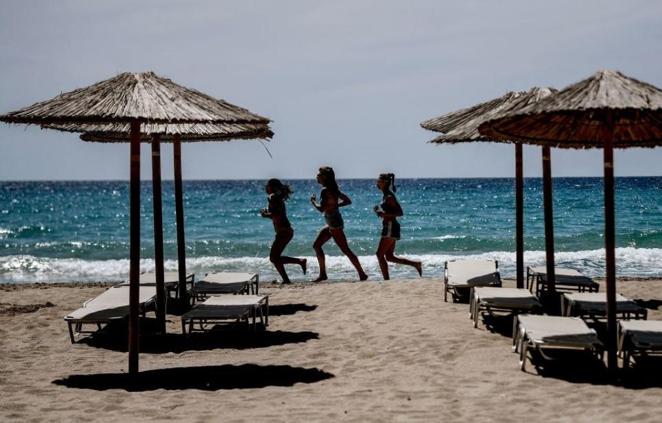 People running on a beach in Greece.