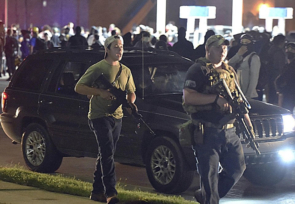 FILE - In this Aug. 25, 2020, file photo, Kyle Rittenhouse, left, with backwards cap, walks along Sheridan Road in Kenosha, Wis., with another armed civilian. Rittenhouse was among a number of armed white men who converged on the city this summer, claiming to protect property owners from arson and theft, one example of political or social unrest that has caused increased anxiety levels among African Americans. (Adam Rogan/The Journal Times via AP, File)