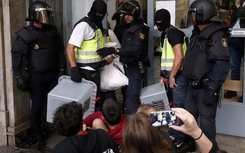 Spanish police officers seize ballot-boxes in a polling station in Barcelona - Credit: PAU BARRENA/AFP/Getty Images