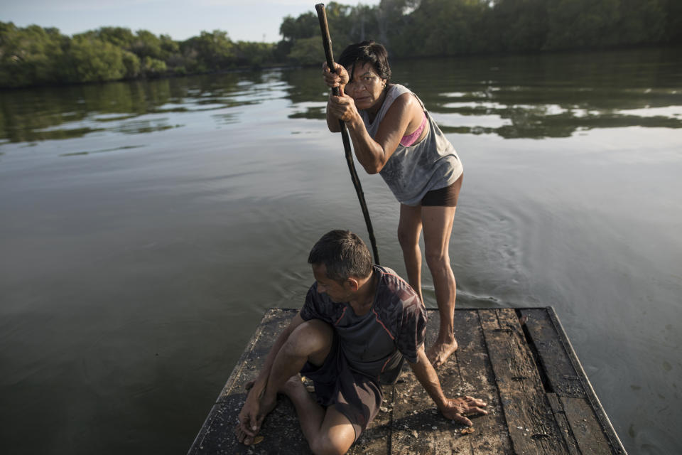 Carmen Garcia paddles a raft as she and her long-time boyfriend Juan Carlos Pirela start collecting their fish nets in hopes of a catch for food to eat in Lake Maracaibo in Cabimas, Venezuela, Nov. 25 2019. For many in Maracaibo, Venezuela's economic crash in the last five years hit especially hard. Once a center of the nation's vast oil wealth, production under two decades of socialist rule has plummeted to a fraction of its high, taking down residents' standard of living. (AP Photo/Rodrigo Abd)
