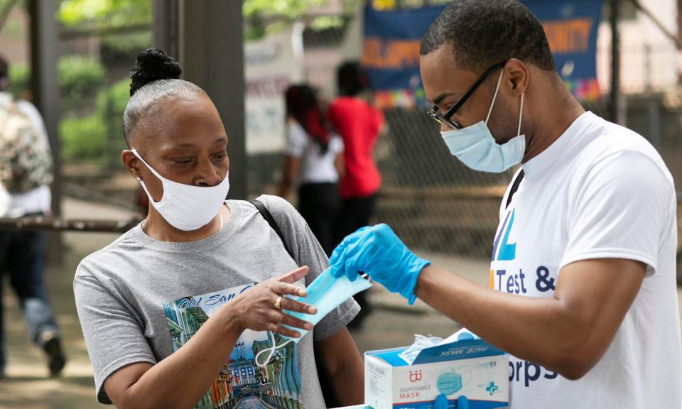 Stephane Labossiere, right, with the Mayor’s Office of Immigrant Affairs, hands out masks and printed information about free coronavirus testing in Brooklyn offered by NYC Health + Hospitals in New York.