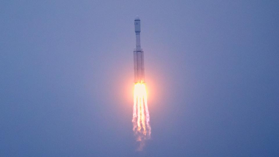 Eine weiße Rakete hebt am graublauen Himmel ab