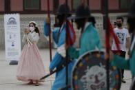 Visitors hold their smartphones while maintaining social distancing during a re-enactment ceremony of the changing of the Royal Guard at the Gyeongbok Palace, one of South Korea's well-known landmarks, in Seoul, South Korea, Friday, July 31, 2020. South Korea's newest coronavirus cases were mostly tied to international arrivals. (AP Photo/Lee Jin-man)