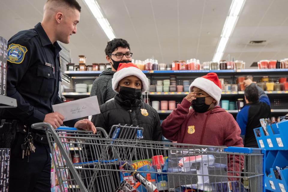 Buckingham Township Police Ofc. Matt Ofner pushes a cart filled with toys picked out by Derek Powers, 9, and Alex Powers 8, of Doylestown, with the help of their uncle, Jose Cortez, 16, during Plumstead Township Police Department's 5th annual Shop with a Cop event at Walmart in Hilltown Township on Tuesday, December 8, 2021. Funded by community donations, the program paired law enforcement officers from 11 local departments with more than 100 kids to help them shop for presents for themselves and their families.