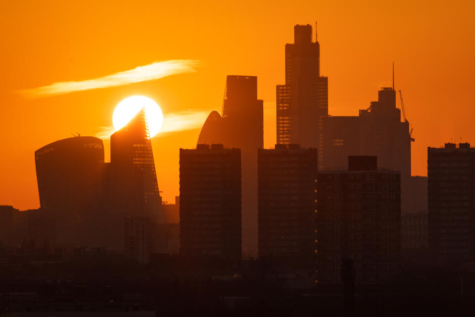 The sun sets behind skyscrapers in the city financial district of London.