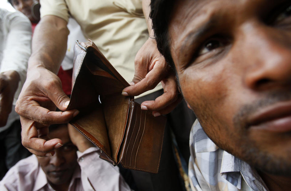 A migrant worker from Bangladesh shows his empty wallet to the camera as workers gather near a government office in Singapore on February 16, 2009. REUTERS/Vivek Prakash