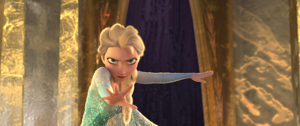 Elsa from Frozen strikes an action pose with her hand extended, standing in front of ice palace