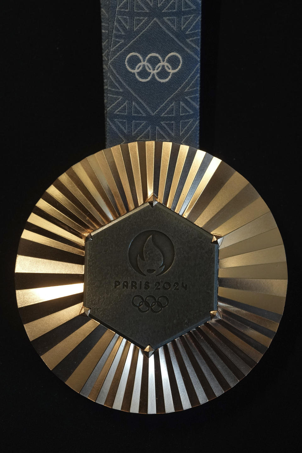 The Paris 2024 Olympic bronze medal is presented to the press, in Paris, Thursday, Feb. 1, 2024. A hexagonal, polished piece of iron taken from the Eiffel Tower is being embedded in each gold, silver and bronze medal that will be hung around athletes' necks at the July 26-Aug. 11 Paris Games and Paralympics that follow. (AP Photo/Thibault Camus)