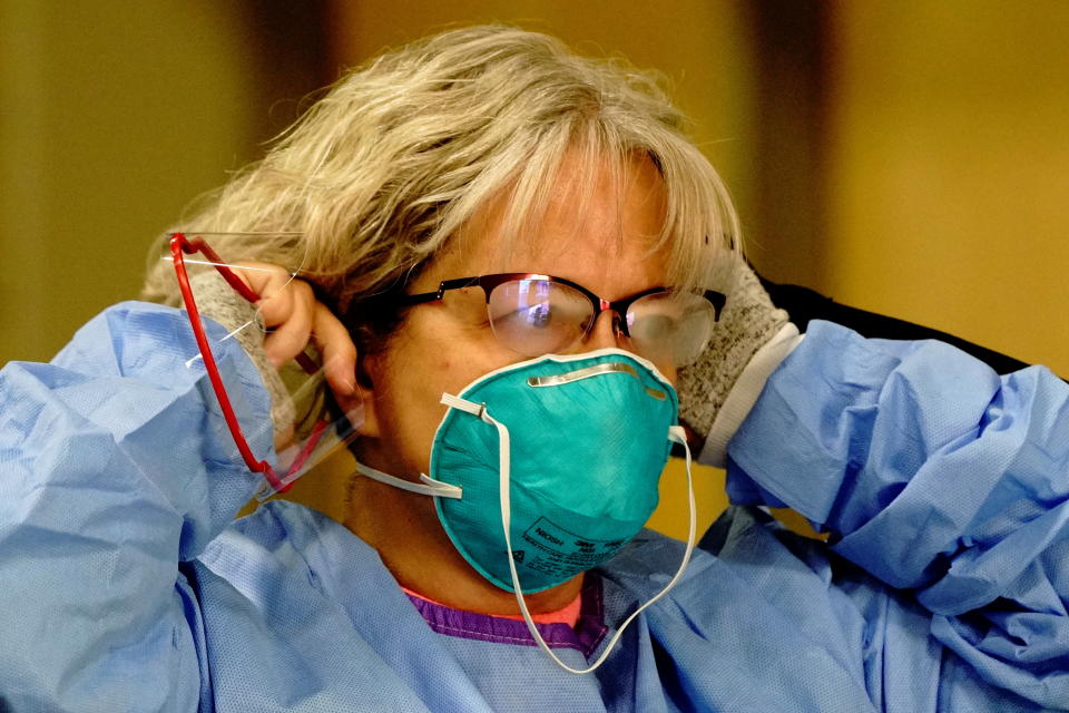 Registered nurse Dana Simmers' glasses fog up as she dons a 3M N95 protective mask before beginning her shift at a drive-thru testing site inside the Bismarck Event Center as the coronavirus disease (COVID-19) outbreak continues in Bismarck, North Dakota, U.S., October 26, 2020. REUTERS/Bing Guan
