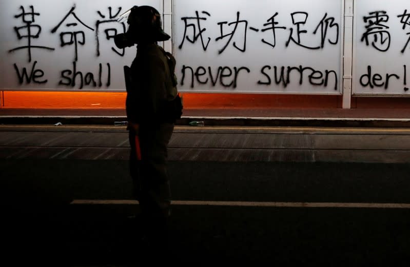 A policeman stands in front of graffiti during a march billed as a global "emergency call" for autonomy, in Hong Kong