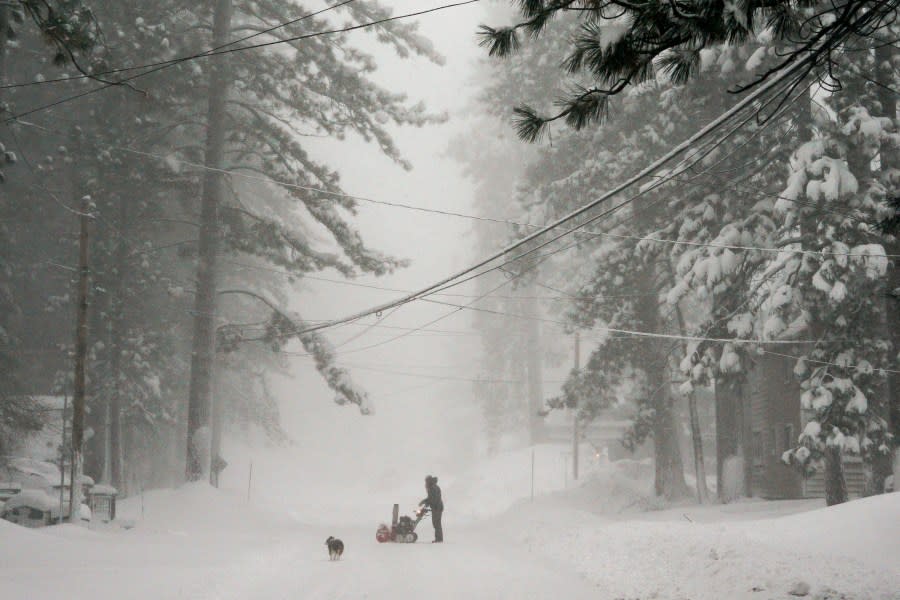 A person tries to clear snow from a road during a storm, Saturday, March 2, 2024, in Truckee, Calif. A powerful blizzard howled Saturday in the Sierra Nevada as the biggest storm of the season shut down a long stretch of Interstate 80 in California and gusty winds and heavy rain hit lower elevations, leaving tens of thousands of homes without power. (AP Photo/Brooke Hess-Homeier)